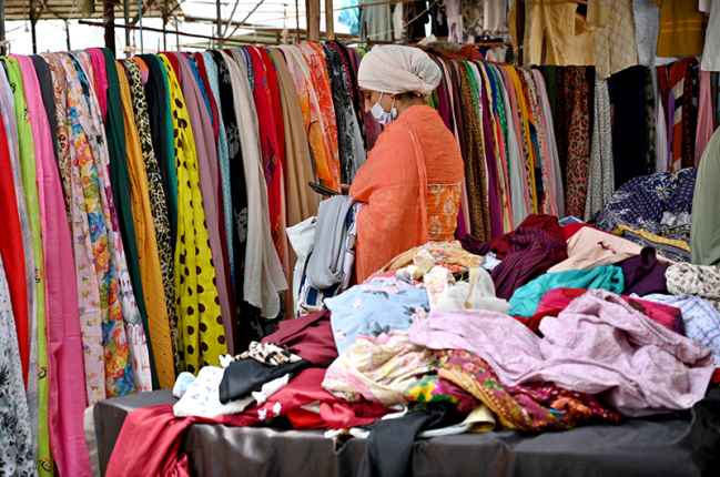 Woman Admires Colorful Stoles at Sunday Bazaar